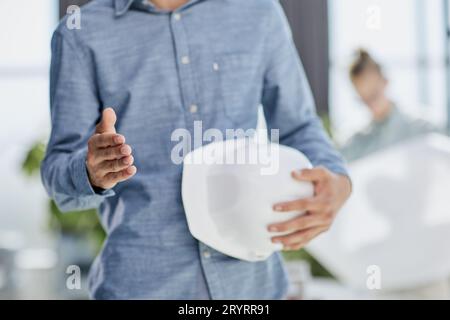 Architect and civil engineer shaking hands while holding hard hat in hand Stock Photo