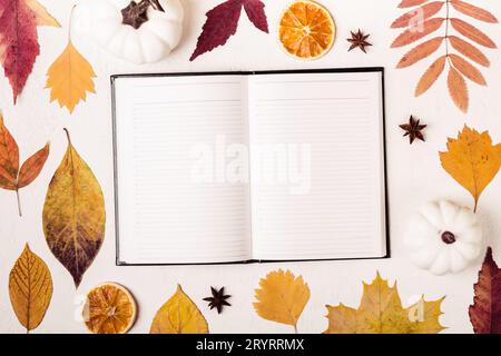 Notepad on white table with autumn leaves pattern Stock Photo