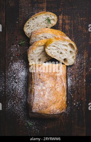 Italian ciabatta bread cut in slices on dark wooden background Stock Photo