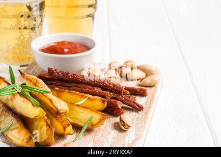 Set of different appetizers for beer are served on a cutting board and glasses with beer Stock Photo