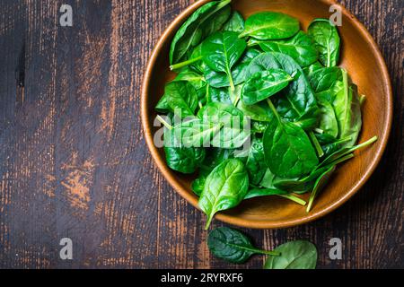 Baby spinach leaves in a bowl on dark background Stock Photo