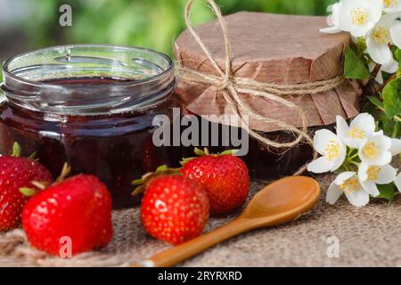 Traditional homemade strawberry jam in jars with bouquet of flowers Stock Photo