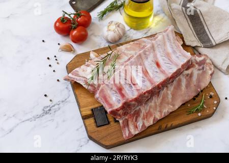 Raw veal calf brisket ribs meat with vegetable and spices on short spare rib for cooking on marble tabletop. Copy space. Stock Photo