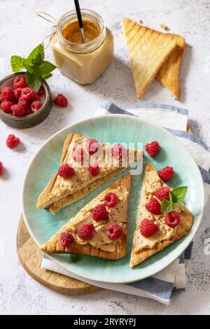Sweet dessert sandwich breakfast. Tasty bread toasted with peanut butter and raspberry on a stone tabletop. Stock Photo
