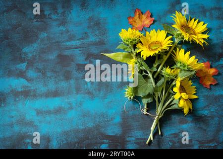 Creative autumn decor of sunflowers and leaves on a blue background. Nature trendy autumn composition. Flat lay, copy space. Stock Photo