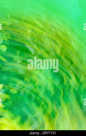 Green art blurred bokeh sparks flying background with motion effect. Green abstract flowing light trails effect. Green dynamic curving light trails. Stock Photo