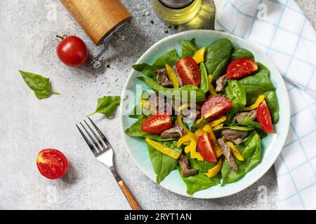 Warm salad of young spinach, chicken liver, tomatoes and grilled peppers with spices and balsamic. Healthy keto diet low carb. V Stock Photo