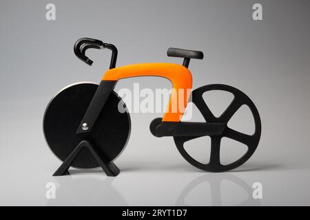 bicycle model used as a pizza cutter utensil, orange framed bike with black wheels isolated on a white background Stock Photo