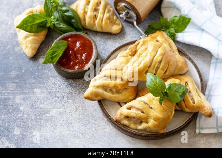 Country style. Tasty food. Mini meat pies with chicken from puff pastry dough on a stone table. View from above. Stock Photo