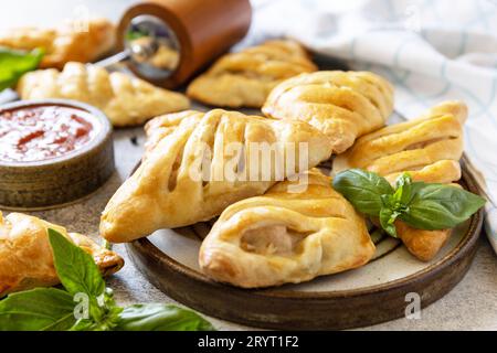 Mini meat pies with chicken from puff pastry dough on a stone table. Country style. Tasty food. Stock Photo
