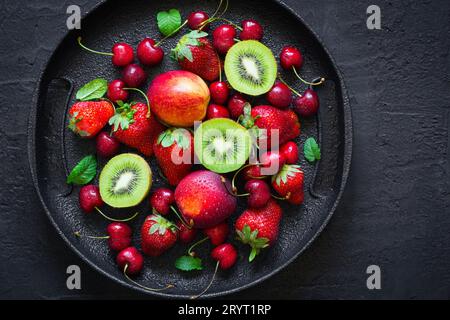 Mix of summer berries and fruits on a black plate. Top view with Stock Photo