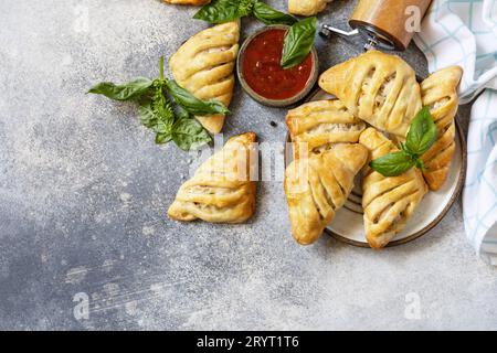 Country style. Tasty food. Mini meat pies with chicken from puff pastry dough on a stone table. View from above. Copy space. Stock Photo