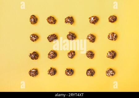 Food pattern of chocolate popcorn on a yellow background Stock Photo