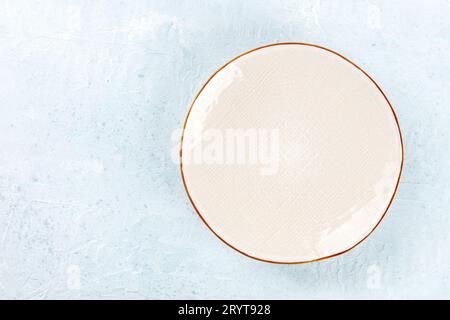 An empty white plate with a gold rim, shot from above on a slate background Stock Photo