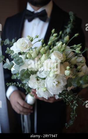 A portrait of a young man wearing a smart suit and holding a bouquet of colorful flowers Stock Photo