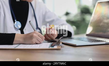Woman physician, nurse or pharmacist wearing white coat writing Stock Photo