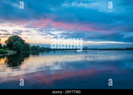 Colorful sunset on the river. Sunset sky reflecting in the mirror water with floating wild ducks Stock Photo
