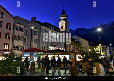 Belltower of the Hospital Church of the Holy Spirit towering over the Christmas market on Maria Theresien Straße, Innsbruck, Austria Stock Photo