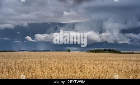 Looming dark storm clouds fill the sky, their ominous forms backlit by ...