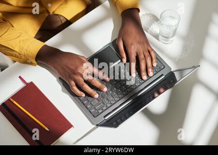 Top view of hands of young African American male entrepreneur or freelancer over laptop keyboard during network or entering information Stock Photo