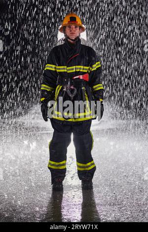 A determined female firefighter in a professional uniform striding through the dangerous, rainy night on a daring rescue mission Stock Photo