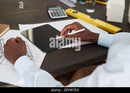 Focus on hands of young male architect with white stylus over tablet screen during work over new engineering project and drawing sketch Stock Photo