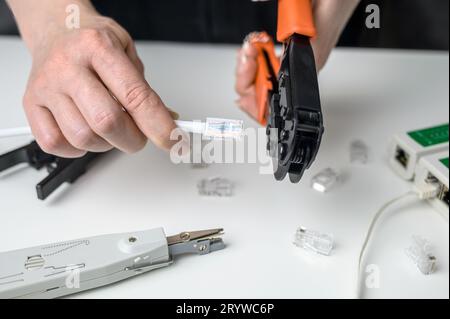 Installation of Internet or telephone line cables using a crimping device. UTP Cat 5 twisted pair ethernet cable crimping tool, RJ45 LAN Cable crimpin Stock Photo