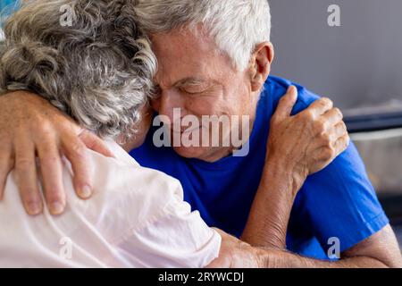 Distressed senior caucasian couple embracing and crying in group therapy session Stock Photo