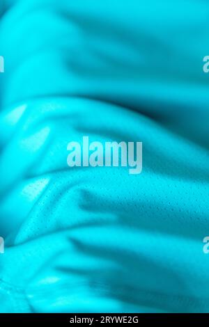 Teal or turquoise coloured polyester-type fabric in closeup with natural light illuminating the texture and folds in the textile. Stock Photo