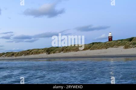 Lighthouse standing on the Dutch coast with a dramatic. and colorful dusk or dawn sky behind it Stock Photo