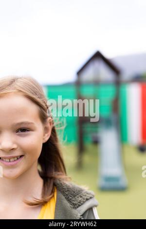 Vertical half face portrait of smiling caucasian schoolgirl in schoolyard, with copy space Stock Photo