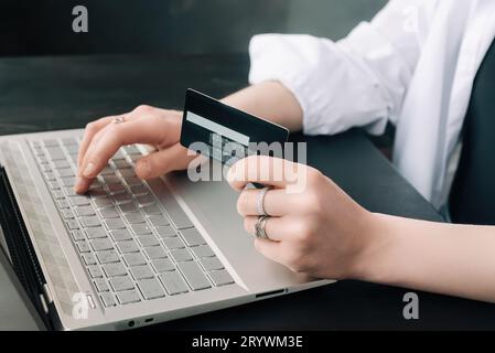 Elegance in E-commerce. Woman's Hands Grasp Credit Card, Navigate Online Shopping with Laptop - Conceptual Image. Chic Shopper. Woman Using Laptop and Stock Photo