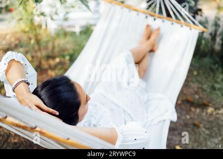 Young female brunette expecting baby in white dress resting on outdoors Stock Photo