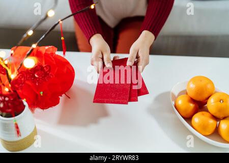 Asian Woman giving red envelope for Lunar New Year celebrations. Hand hold red packet Stock Photo