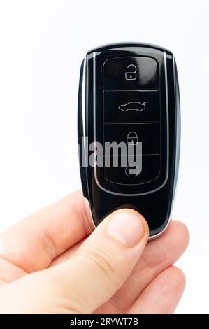 Hand hold black car key isolated on white studio background close up view Stock Photo