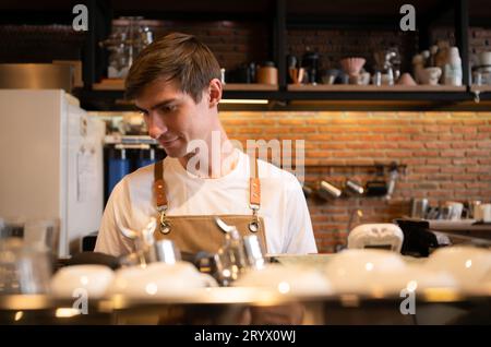 Portrait of a young male barista preparing coffee in a coffee shop Stock Photo