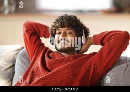 Happy Young Indian Guy Listening Music In Wireless At Home Stock Photo