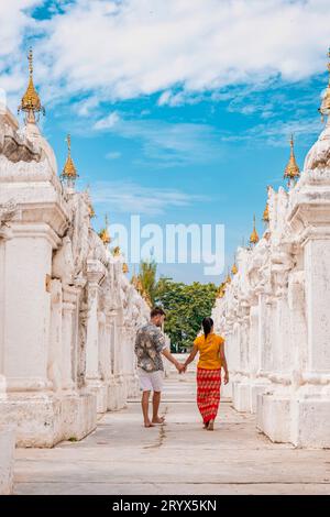 Kuthodaw pagoda in Mandalay, Burma Myanmar, happy young couple men and woman on vacation in Myanmar walking by white temple pago Stock Photo