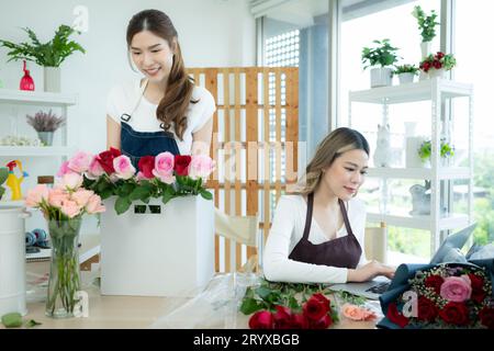 Two asian female florist working at flower shop with laptop. Stock Photo