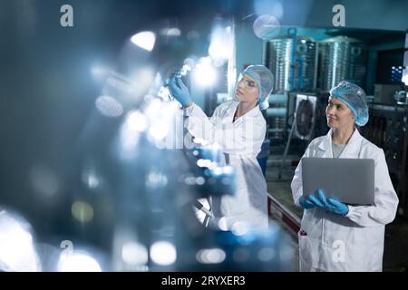 Portrait of a scientist in the drinking water factory using a ladder, looking at the water tanks above and examining with a coll Stock Photo