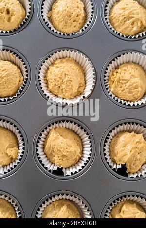 Scooping cupcake batter with a dough scoop into cupcake foil liners to bake  gingerbread cupcakes Stock Photo - Alamy