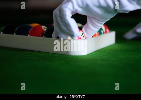 Man's hand and Cue arm playing snooker game or preparing aiming to shoot pool balls on a green billiard table. Colorful snooker Stock Photo