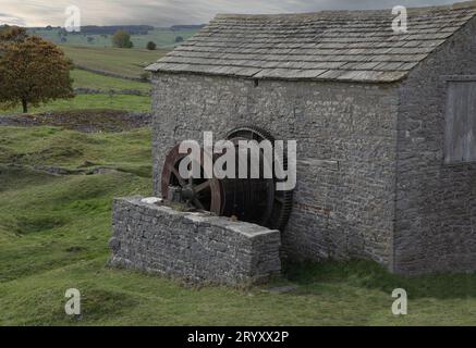 Winding gear of a disused lead mine on the side of an old stone building Stock Photo
