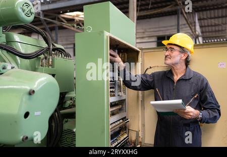 Senior engineer inspects the electrical system and repairs the mechanical system in the machine control cabinet. in order for th Stock Photo