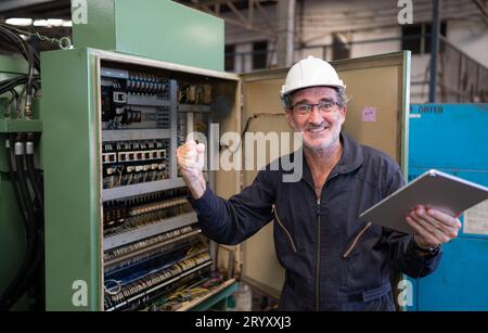 Senior engineer inspects the electrical system and repairs the mechanical system in the machine control cabinet. in order for th Stock Photo