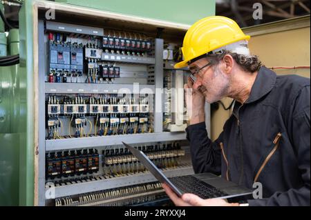 Senior engineer inspects the electrical system and repairs the mechanical system in the machine control cabinet. in order for th Stock Photo