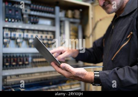 Senior engineer inspects the electrical system and repairs the mechanical system in the machine control cabinet. in order for th Stock Photo