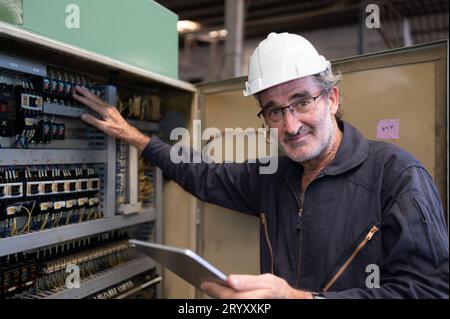 Senior engineer inspects the electrical system and repairs the mechanical system in the machine control cabinet. in order for th Stock Photo