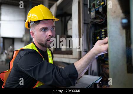 The engineer inspects the electrical system and repairs the mechanical system in the machine control cabinet. in order for the m Stock Photo