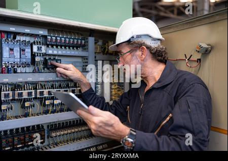 Senior engineer inspects the electrical system and repairs the mechanical system in the machine control cabinet. in order for th Stock Photo